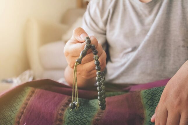 A man sitting on a bed holding a beaded purse